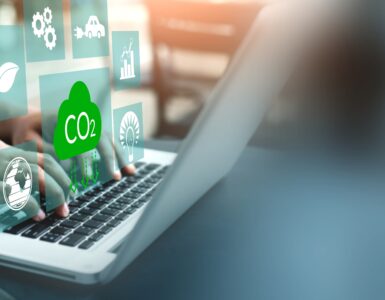 Hands type on the keyboard of a laptop with symbols overlaid representing CO2, energy, emissions, climate.